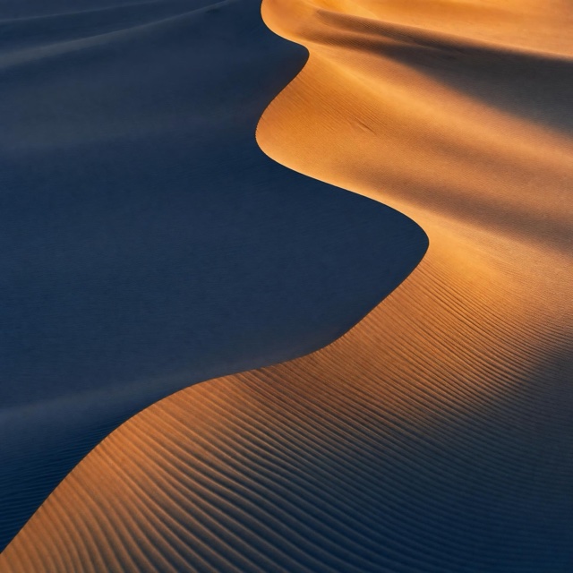 AI-generated: Copper desert dunes with fine ripples and indigo shadows