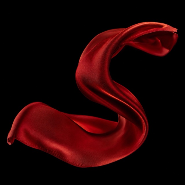 AI-generated: Crimson silk suspended against a dark studio background
